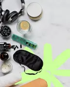 Wellness flatlay with headphones, supplement bottles, sleep mask, yoga mat, and candle